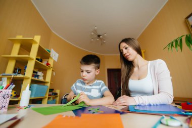 Genç bir anne evde oğluyla ev ödevi yapıyor. Ebeveynler ve eğitim