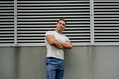 Sportif bir adam gri bir duvarın yanında duruyor. Yaşam biçimi