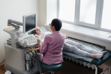 Hamile bir kız klinikte karnının ultrasonuna giriyor. Tıbbi muayene