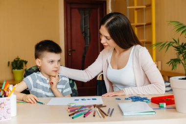 Genç bir anne evde oğluyla ev ödevi yapıyor. Ebeveynler ve eğitim