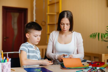 Genç bir anne evde oğluyla ev ödevi yapıyor. Ebeveynler ve eğitim