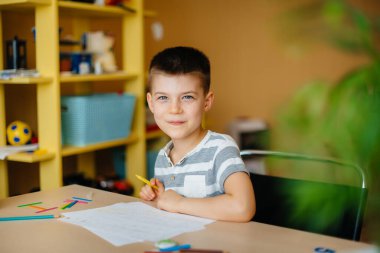 Okul çağındaki bir çocuk evde ödev yapar. Okulda eğitim.