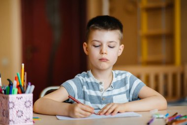 Okul çağındaki bir çocuk evde ödev yapar. Okulda eğitim.