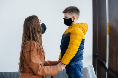 Karantina sırasında çocuklu bir anne maske takıyor. Salgın, koronavirüs.
