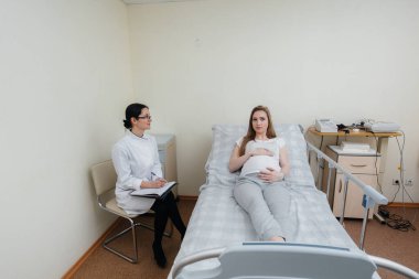 Doktor, klinikte genç hamile bir kıza tavsiye ve hizmet veriyor. Tıbbi muayene