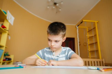 Okul çağındaki bir çocuk evde ödev yapar. Okulda eğitim.