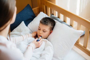 Ateşi ve ateşi olan bir anne çocuğuna bakar. Hastalık ve sağlık hizmetleri