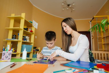 Genç bir anne evde oğluyla ev ödevi yapıyor. Ebeveynler ve eğitim