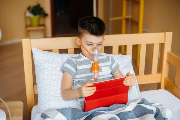 Bir çocuk akciğer solunumu sırasında tabletle oynuyor. İlaç ve bakım