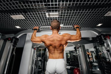 Spor salonunda barfiks çeken bir sporcu. Fitness, vücut geliştirme