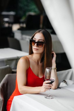 Güzel bir genç kız güzel bir evin verandasında oturur ve şarap içer. Tatil.