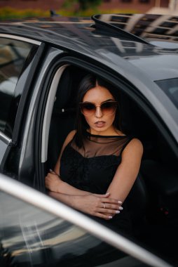 Siyah elbiseli, birinci sınıf bir arabada oturan şık bir genç kız. İş modası ve tarzı