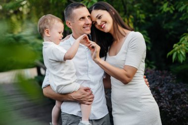 Oğulları gün batımında parkta yürüyen mutlu bir aile. Mutluluk. Aşk