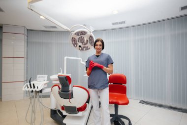 Dişçi dişçi koltuğunun yanında duruyor.