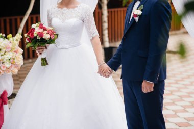 Güzel ve sofistike bir düğün buketi gelini damadın yanında tutuyor. Düğün buketi ve yüzükler.