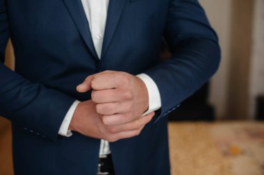 Şık genç adam kol düğmelerinin düğmelerini ilikliyor. Biçim