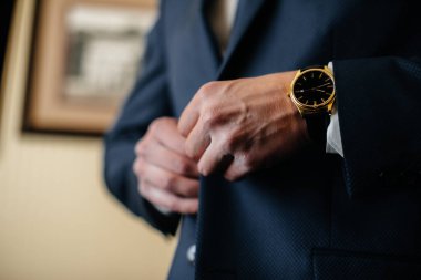 Şık genç adam kol düğmelerinin düğmelerini ilikliyor. Biçim