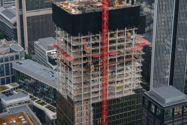 Construction of a modern high-rise skyscraper with cranes in the center of the metropolis. Construction