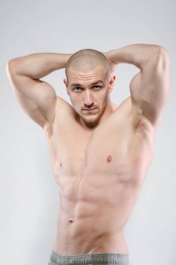 Beyaz arka planda üstsüz poz veren seksi bir sporcu. Fitness