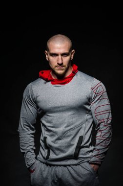 Stüdyoda kapüşonlu karanlık bir arka plana karşı duran sportif bir adam. Spor, güzellik