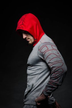 Stüdyoda kapüşonlu karanlık bir arka plana karşı duran sportif bir adam. Spor, güzellik