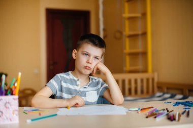 Okul çağındaki bir çocuk evde ödev yapar. Okulda eğitim.