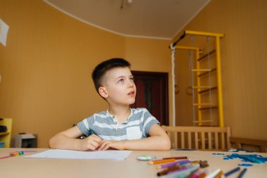 Okul çağındaki bir çocuk evde ödev yapar. Okulda eğitim.