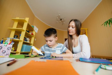 Genç bir anne evde oğluyla ev ödevi yapıyor. Ebeveynler ve eğitim