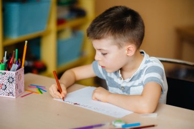 Okul çağındaki bir çocuk evde ödev yapar. Okulda eğitim.