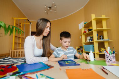 Genç bir anne evde oğluyla ev ödevi yapıyor. Ebeveynler ve eğitim