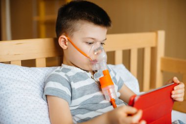Bir çocuk akciğer solunumu sırasında tabletle oynuyor. İlaç ve bakım