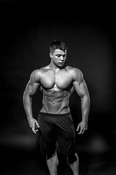Sexy young athlete posing on a black background in the Studio. Fitness, bodybuilding, black and white