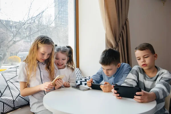 Los Niños Sientan Una Mesa Café Juegan Juntos Los Teléfonos —  Fotos de Stock