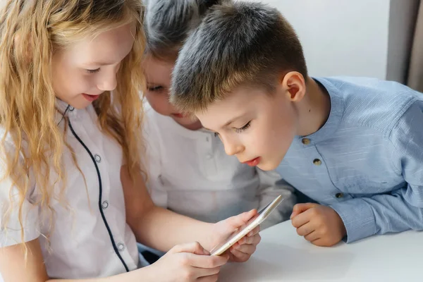 子供たちはカフェのテーブルに座り 携帯電話を一緒に再生します 近代芸能 — ストック写真