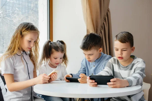 Dzieci Siedzą Przy Stole Kawiarni Bawią Się Razem Telefonami Komórkowymi — Zdjęcie stockowe
