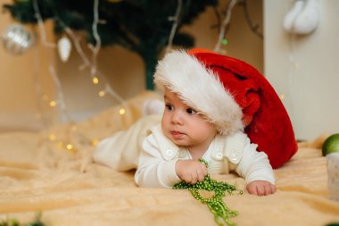 Sevimli gülümseyen bebek, Noel ağacının altında yatıyor ve hediyelerle oynuyor. Noel ve Yeni Yıl kutlamaları