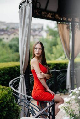 Güzel bir genç kız güzel bir evin verandasında duruyor..