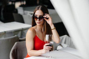 Güzel bir genç kız güzel bir evin verandasında oturur ve şarap içer. Tatil.