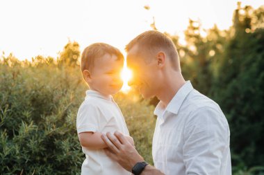 Baba ve oğul gün batımında parkta yürüyorlar. Mutluluk. Aşk