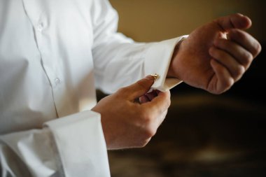Şık genç adam kol düğmelerinin düğmelerini ilikliyor. Biçim