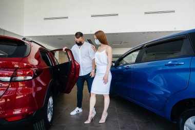 Young couple in masks selects a new vehicle and consult with a representative of the dealership in the period of the pandemic. Car sales, and life during the pandemic clipart