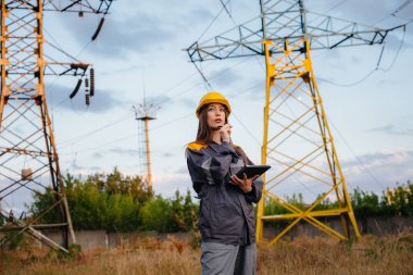 Genç bir mühendis, elektrik hattının ekipmanlarını denetleyip kontrol ediyor. Enerji