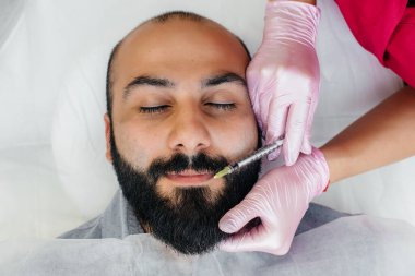 Dudak büyütme ve sakallı bir adam için kırışıklık giderme için estetik ameliyat. Kozmetoloji