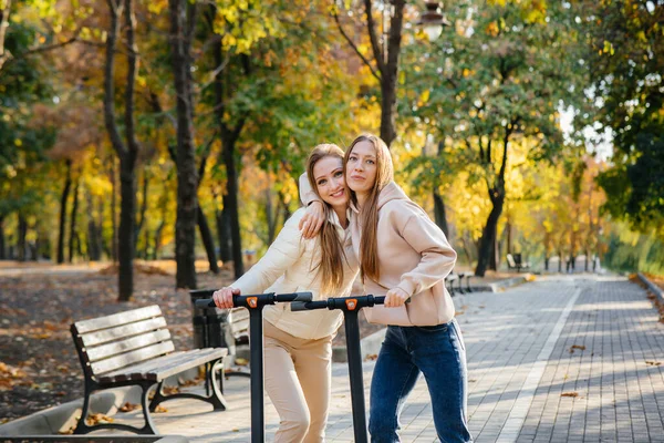 Duas Meninas Bonitas Jovens Montam Scooters Elétricos Parque Dia Quente — Fotografia de Stock