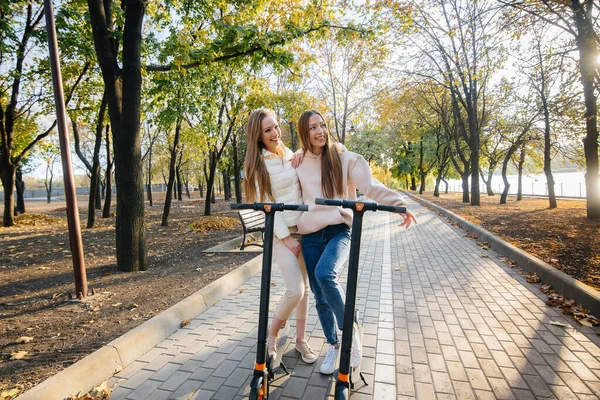 Duas Meninas Bonitas Jovens Montam Scooters Elétricos Parque Dia Quente — Fotografia de Stock