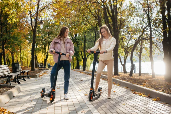 Zwei Junge Schöne Mädchen Fahren Einem Warmen Herbsttag Elektroroller Park — Stockfoto