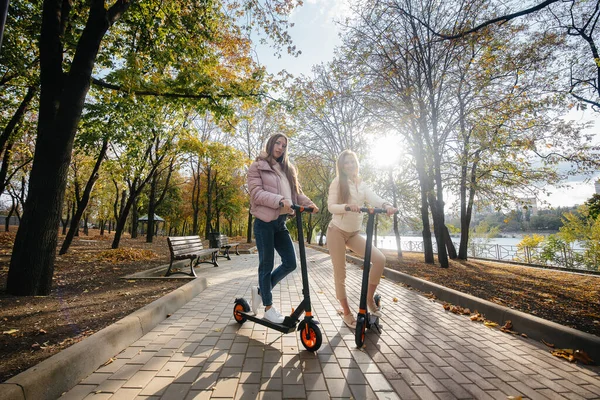 Two Young Beautiful Girls Ride Electric Scooters Park Warm Autumn — Stock Photo, Image