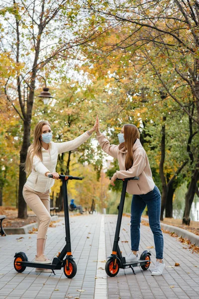 Zwei Junge Hübsche Mädchen Masken Fahren Einem Warmen Herbsttag Elektroroller — Stockfoto