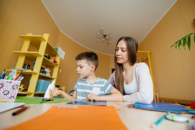 Genç bir anne evde oğluyla ev ödevi yapıyor. Ebeveynler ve eğitim