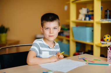Okul çağındaki bir çocuk evde ödev yapar. Okulda eğitim.